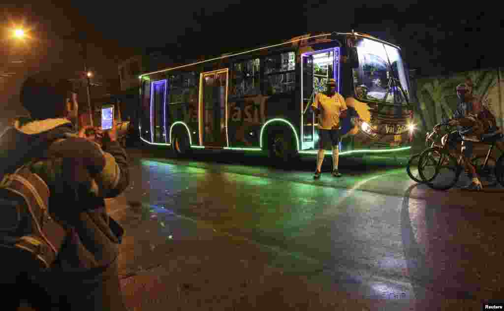 Bus driver Edilson, 45, also known as "Fumassa", is photographed wearing a Brazil national soccer team jersey outside a city bus decorated with the colors of the Brazilian flag and 2014 World Cup icons, in Santo Andre, on the outskirts of Sao Paulo, June 18, 2014.