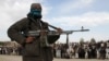 FILE - Seorang anggota Taliban dan orang lain berdiri di lokasi saat eksekusi tiga pria di Provinsi Ghazni, Afghanistan, 18 April 2015. Pada 22 Februari 2024, otoritas Taliban secara terbuka mengeksekusi dua pria yang dihukum karena pembunuhan dalam kasus terpisah.