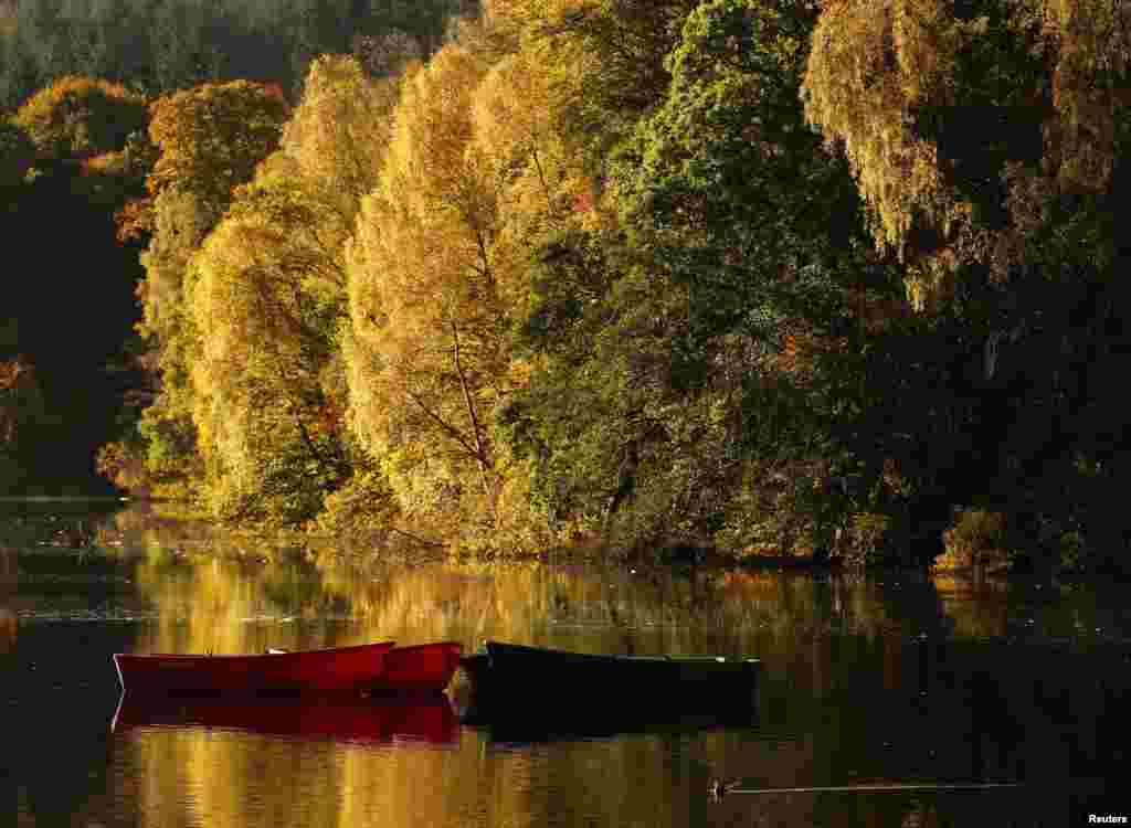 Moored boats are seen on Loch Faskally, as autumn leaves are reflected in the water, in Pitlochry, Scotland.