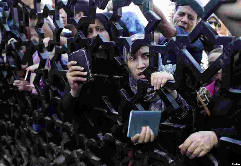 Palestinians standing behind the gate of Rafah crossing in the southern Gaza Strip hold their passports as they try to cross into Egypt. At least 74 Palestinians, most of them civilians, have been killed in Israel's Gaza offensive, Palestinian officials said.