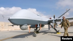 U.S. Air Force officer passes in front of a MQ-9 Reaper drone, one of a squadron that has arrived to step up the fight against the Taliban, at the Kandahar air base, Afghanistan, Jan. 23, 2018. 