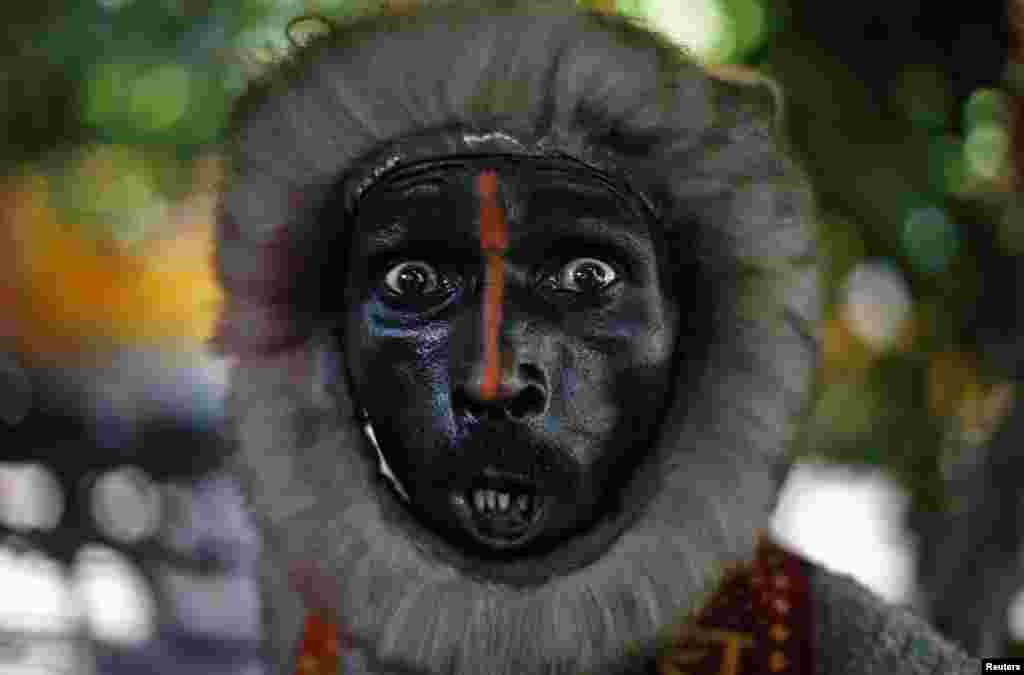 A man dressed as a monkey reacts as he begs on a street in New Delhi, India.