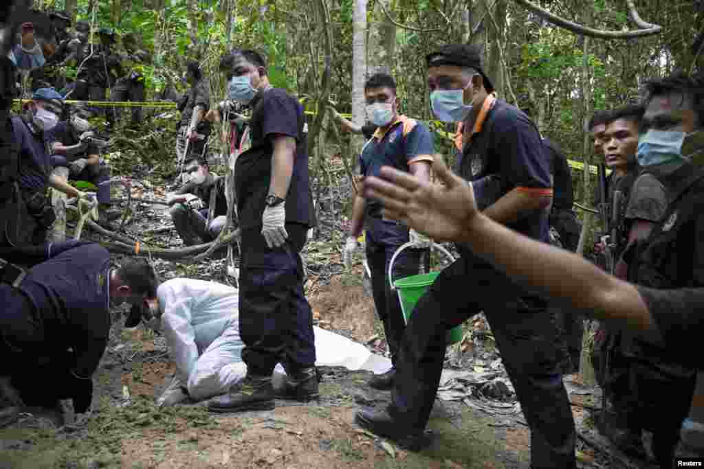 Tim forensik polisi menggali kuburan dekat kamp perdagangan manusia yang ditelantarkan di hutan dekat perbatasan Thailand di Bukit Wang Burma, Malaysia utara (27/5). (Reuters/Damir Sagolj)