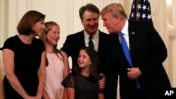 FILE - President Donald Trump talks with Judge Brett Kavanaugh his Supreme Court nominee, and his family in the East Room of the White House, July 9, 2018, in Washington. 