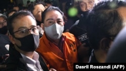 Polisi mengawal terpidana korupsi Djoko Tjandra (tengah), setibanya di bandara Jakarta, 30 Juli 2020, setelah ditangkap di Malaysia dalam pelariannya yang menyebabkan beberapa jenderal polisi diberhentikan karena keterlibatannya. (Foto: AFP/Dasril Roszand