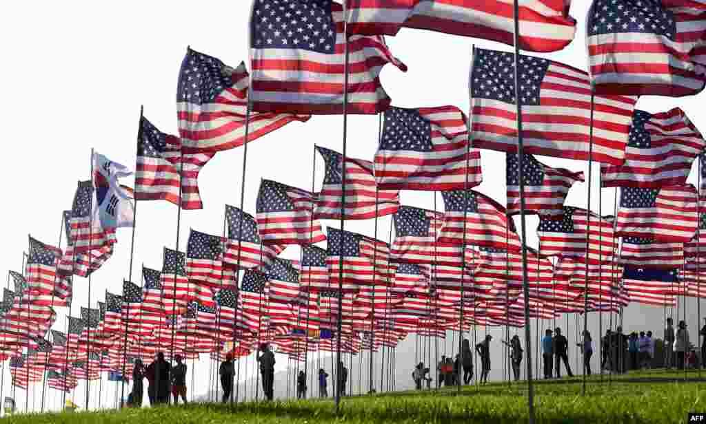 People help with the display of U.S. flags to commemorate the 20th anniversary of 9/11 with the annual Waves of Flags display and remembrance at Pepperdine University in Malibu, California, Sept. 8. 2021.