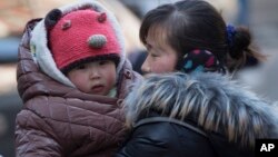 Une Chinoise avec son enfant à Pékin, en Chine, le 6 mars 2014. (AP Photo/Vincent Thian) 