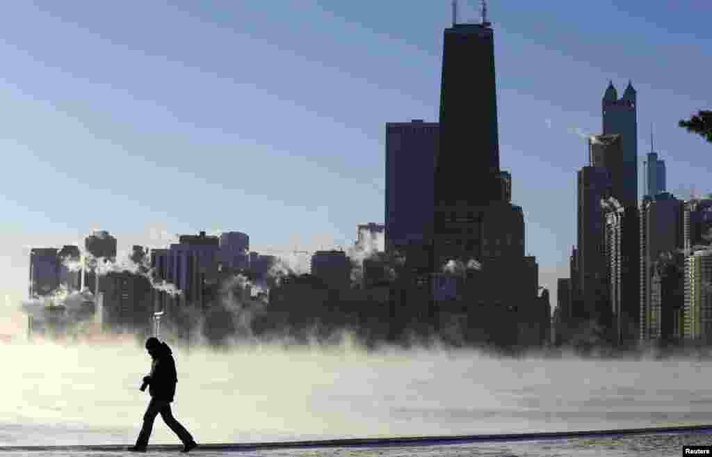 Seorang pria berjalan ketika asap laut Arktik naik dari Danau Michigan di Chicago, Illinois, 6 Januari 2014.