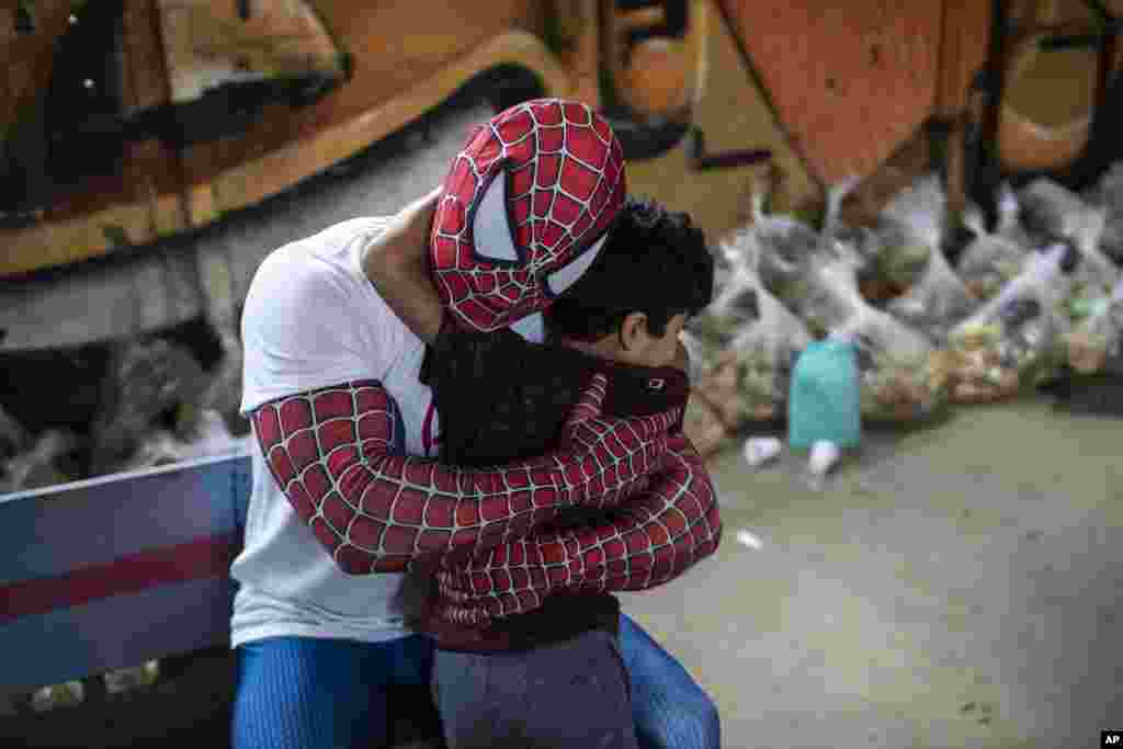 A volunteer dressed as Spiderman embraces a child in the Jardim Gramacho favela of Rio de Janeiro, Brazil, Oct. 30, 2021, during a food kit delivery donated by the non-governmental organization "Covid Sem Fome".