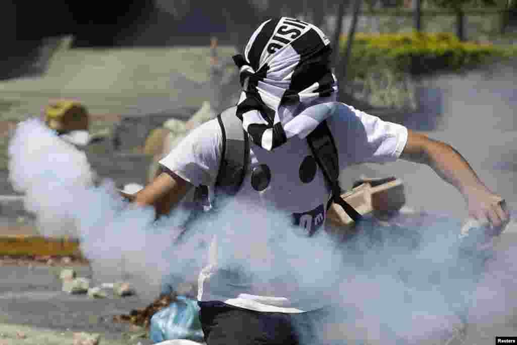 Seorang demonstran anti-pemerintah melemparkan kaleng berisi gas air mata ke arah polisi dalam aksi protes di Caracas, Venezuela. 