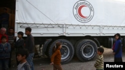 People stand next to Syrian Arab Red Crescent truck in the town of Nashabiyeh, eastern Ghouta in Syria, Nov. 28, 2017. 