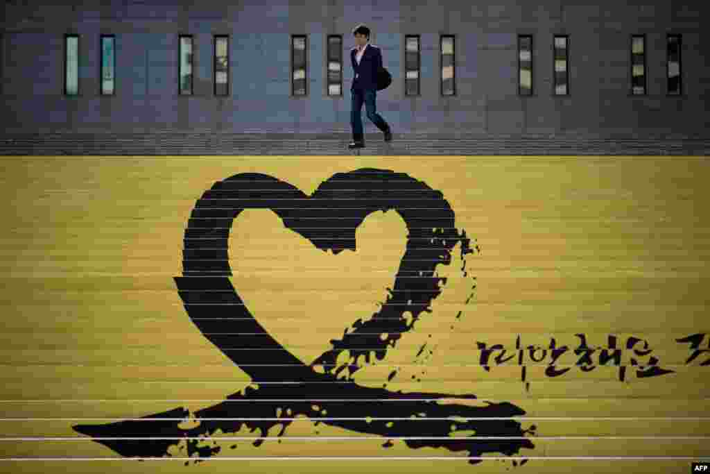 Seorang pria menuruni tangga melewati sebuah tanda penghormatan kepada para korban feri Sewol, di Seoul, Korea Selatan. Korban tewas dikonfirmasi berjumlah 273 orang, tidak termasuk 31 korban yang masih belum diketahui, setelah empat jenazah lagi ditemukan dari kapal yang tenggelam itu. 