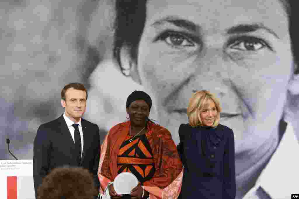 Cameroonian activist Aissa Doumara Ngatansou (C) poses for a photo with French President Emmanuel Macron (L) and his wife Brigitte Macron (R) after she received the Simone Veil prize, at the Elysee Palace, in Paris, on March 8, 2019 during International Women's Day.