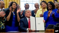 President Donald Trump holds up the Historically Black Colleges and Universities HBCU Executive Order after signing it, Feb. 28, 2017, in the Oval Office in the White House in Washington.