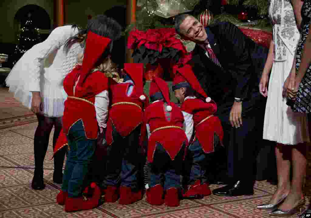Presiden AS Barack Obama tertawa sementara anak-anak berpakaian Elf berebut hadiah Natal dari keluarga Presiden Obama di gedung Museum National di Washington DC.