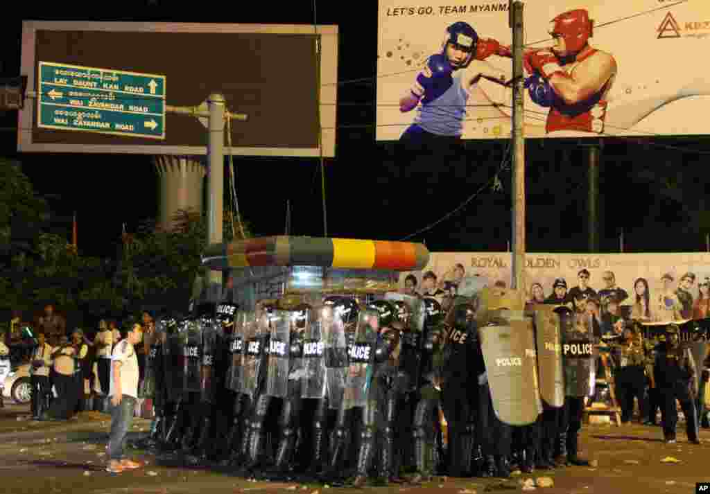 Burma riot police stand guard near Thuwunna stadium in Rangoon, after hundreds of angry football fans destroyed and burnt posters and flags after Burma lost 1-0 to Indonesia in the 27th Southeast Asian Games.
