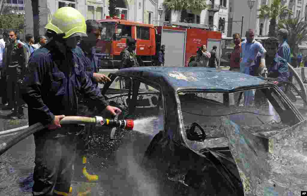 Syrian firefighters extinguish a burned car at the scene of a powerful explosion which occurred in the central district of Marjeh, Damascus, Syria, April 30, 2013.