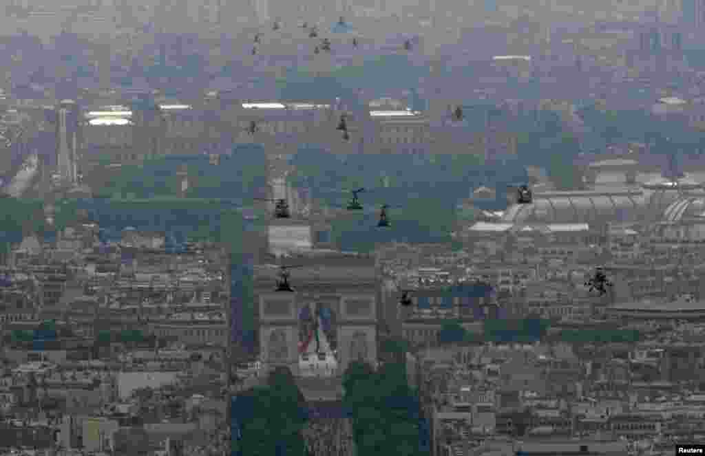 Helikopter-helikopter angkatan darat Perancis mendekati gerbang Arc de Triomphe selama parade Hari Bastille di Paris (14/7). (Reuters/Philippe Wojazer)