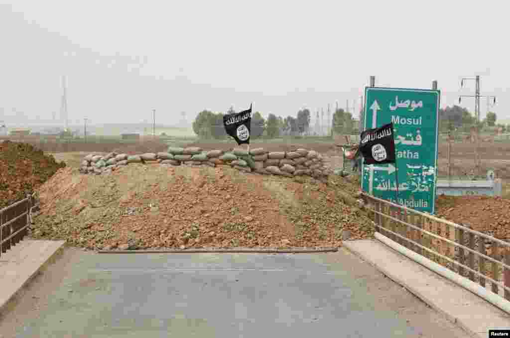 Islamic State flags flutter on the Mullah Abdullah bridge where members of the Kurdish security forces and the Islamic State are holding fort behind sandbags on different ends of the bridge, in southern Kirkuk, Sept. 29, 2014.