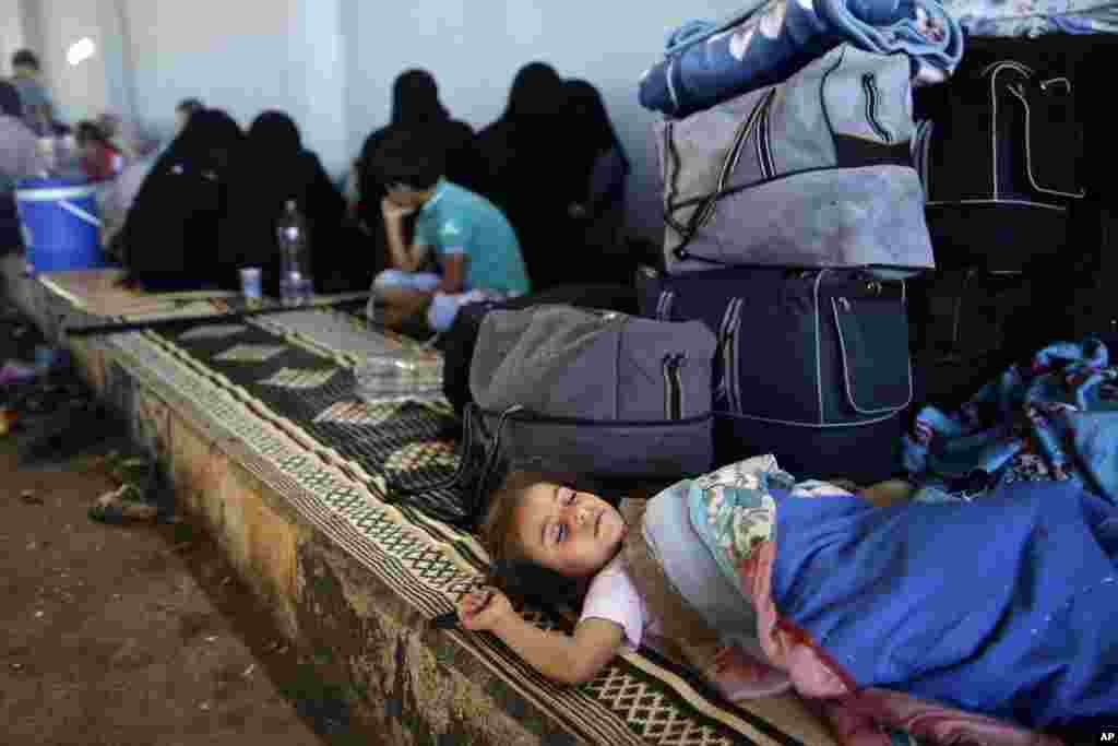 A Syrian girl, who fled her home with her family due to fighting between the Syrian army and the rebels, sleeps by her family's belongings, near the Syrian town of Azaz, Aug. 23, 2012.