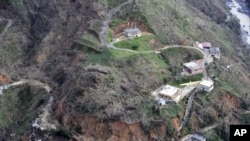 This photo made available by the U.S. Coast Guard, shows homes near a washed out road in Utuado, Puerto Rico, Oct. 3, 2017. 