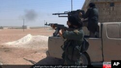 This undated image posted online July 18, 2016, by supporters of the Islamic State militant group on an anonymous photo-sharing website, shows Islamic State fighters firing their weapons during clashes with the Kurdish-led Syria Democratic Forces in Manbij, in Aleppo province, Syria.