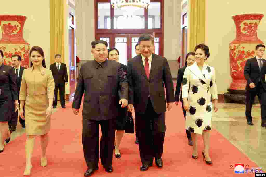 North Korean leader Kim Jong Un and wife Ri Sol Ju, and Chinese President Xi Jinping and wife Peng Liyuan walk together in Beijing, China, in this undated photo released by North Korea's Korean Central News Agency (KCNA) in Pyongyang, March 28, 2018.