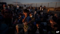 Refugees and migrants wait to board buses after their arrival at the port of Lavrio, Greece, about 75 kilometers south of Athens, on Sept. 29, 2020. 