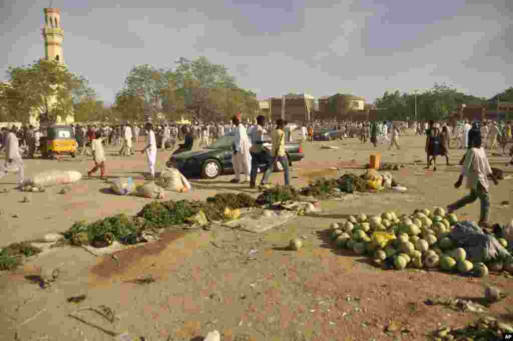 Mutane sun taru su na kallo a inda bam ya tashi a babban Masallacin Jumma'a na Kano, Jumma'a 28 Nuwamba, 2014. Mutane da yawa sun rasa rayukansu, kuma jami'ai suka ce watakila yawan wadanda zasu hallaka zai karu.