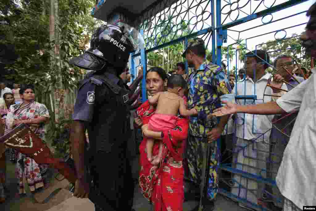 A Buddhist woman walks through the gate of a temple as a policeman stands guard after an attack on the temple by Muslims, in Cox's Bazar, Bangladesh, October 1, 2012.