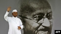 Nhà tranh đấu chống tham nhũng Anna Hazare vẫy tay bên cạnh bức chân dung của thánh Mahatma Gandhi trong cuộc tuyệt thực ở New Delhi, Ấn Ðộ, ngày 20 tháng 8, 2011