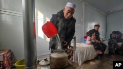 Seorang penduduk merebus air di sebuah hunian sementara bagi penyintas gempa di Desa Meipo, Provinsi Gansu, China, Kamis, 21 Desember 2023. (Foto: Xinhua News Agency via AP)