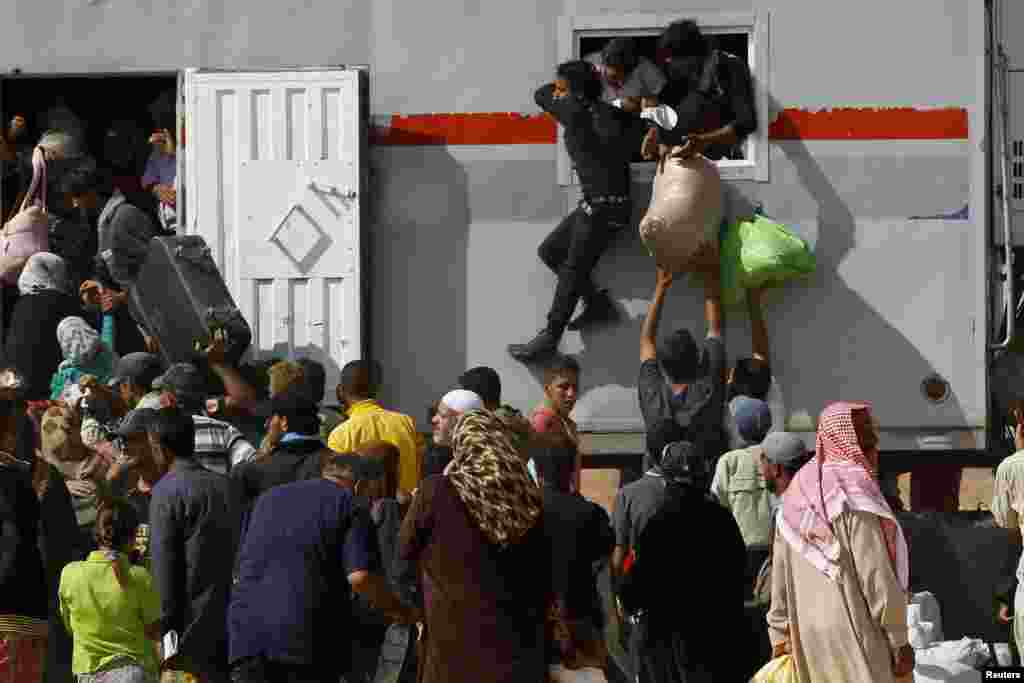 Para pengungsi Suriah antre masuk ke truk yang akan membawa mereka dari kamp pengungsi Al-Zaatri di Mafraq, Yordania, ke kampung halaman di Suriah (30/7). (Reuters/Muhammad Hamed)
