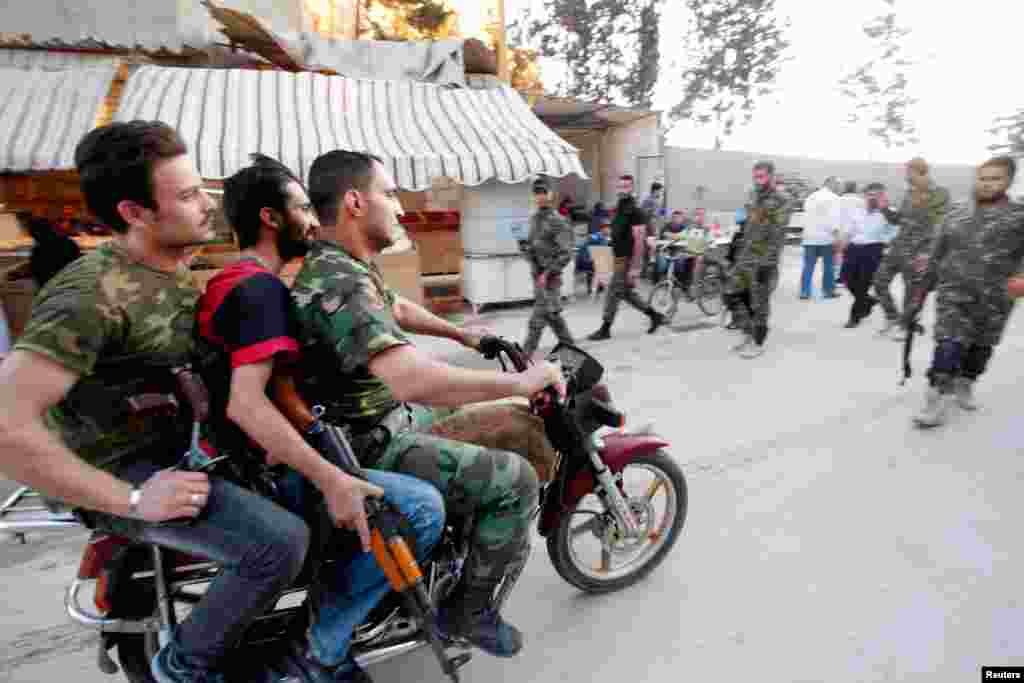 Shi'ite fighters ride through the Sayeda Zainab area of Damascus with their weapons, May 28, 2013.