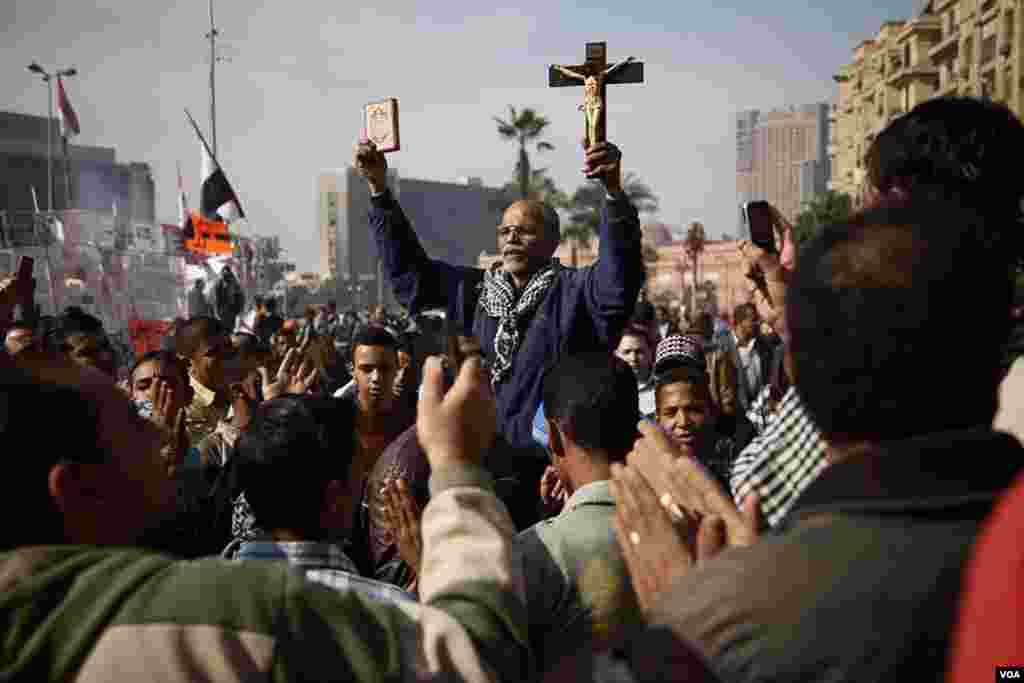 A protester in Tahrir Square holds up a copy of the Koran and a Christian cross, November 30, 2012. (Y. Weeks/VOA)