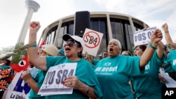 FILE - Lydia Balderas, left, and Merced Leyua, right, join others as they protest against a sanctuary cities bill outside the federal courthouse in San Antonio, June 26, 2017.