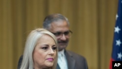 Justice Secretary Wanda Vazquez is accompanied by her husband Judge Jorge Diaz during her swearing in ceremony as Puerto Rico's new governor, in San Juan, Puerto Rico, Wednesday, Aug. 7, 2019. 