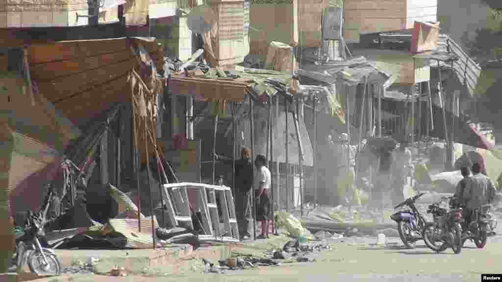 Residents are seen near damaged buildings at Marat al-Numan, near the northern province of Idlib, Syria, October 23, 2012.
