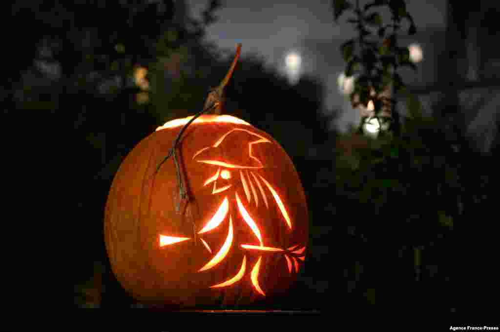 A jack-o'-lantern made with a carved pumpkin representing a witch and her broom, during Halloween night, in Lausanne, Switzerland, Oct. 31, 2021.