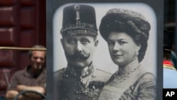 Tourists looking at exhibits in Sarajevo museum, including portraits of Archduke Franz Ferdinand and Sofia von Hochenberg, in Sarejevo, Saturday, June 28, 2014