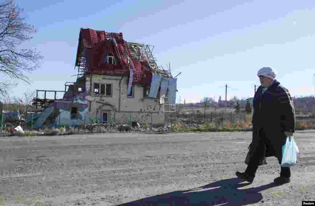 A woman walks near a house damaged by recent shelling in the village of Semyonovka, near Slovyansk, eastern Ukraine, Oct. 27, 2014.