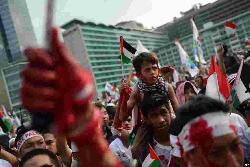 Demonstran di Indonesia, beberapa memerciki wajahnya dengan cat merah, melakukan unjuk rasa besar-besaran di Jakarta mendukung Palestina dan mengutuk serangan Israel di Gaza. 