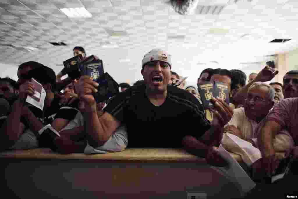 A man trying to cross into Egypt shouts as he holds his and other family members' passports while he waits at the Rafah crossing between Egypt and the southern Gaza Strip, July 16, 2014.