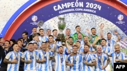 Penyerang Argentina Lionel Messi mengangkat trofi saat merayakan kemenangan pertandingan sepak bola final turnamen Conmebol 2024 Copa America antara Argentina dan Kolombia di Stadion Hard Rock, di Miami, Florida pada 14 Juli 2024. (Foto: AFP)