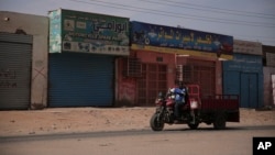 FILE - A man drives past shuttered shops after a military coup unseated the country 's civilian government, in Khartoum, Sudan, Oct. 28, 2021. 