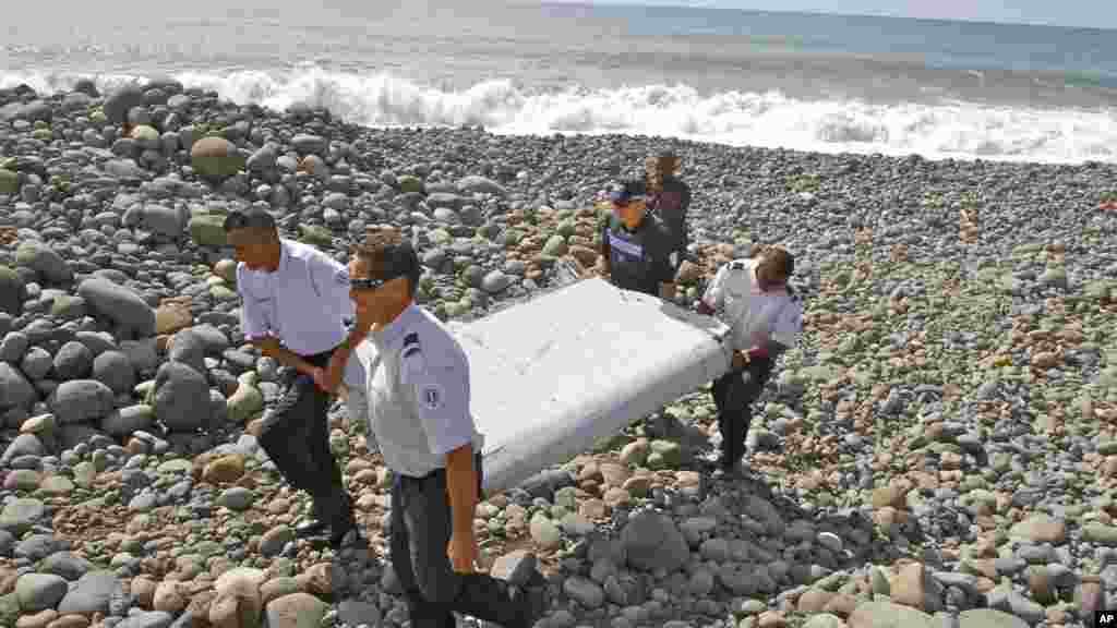 Des gendarmes et policiers français portent un morceau d'avion trouvé sur la plage de Saint-André, 29 juillet 2015.