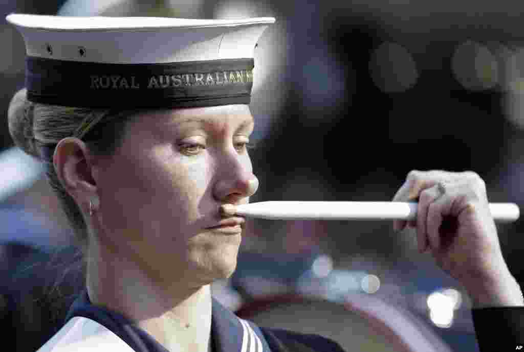 Pemain drumband Angkatan Laut Australia menyentuhkan stick ke wajahnya saat parade memperingati korban perang pada hari ANZAC di Sydney, Australia.
