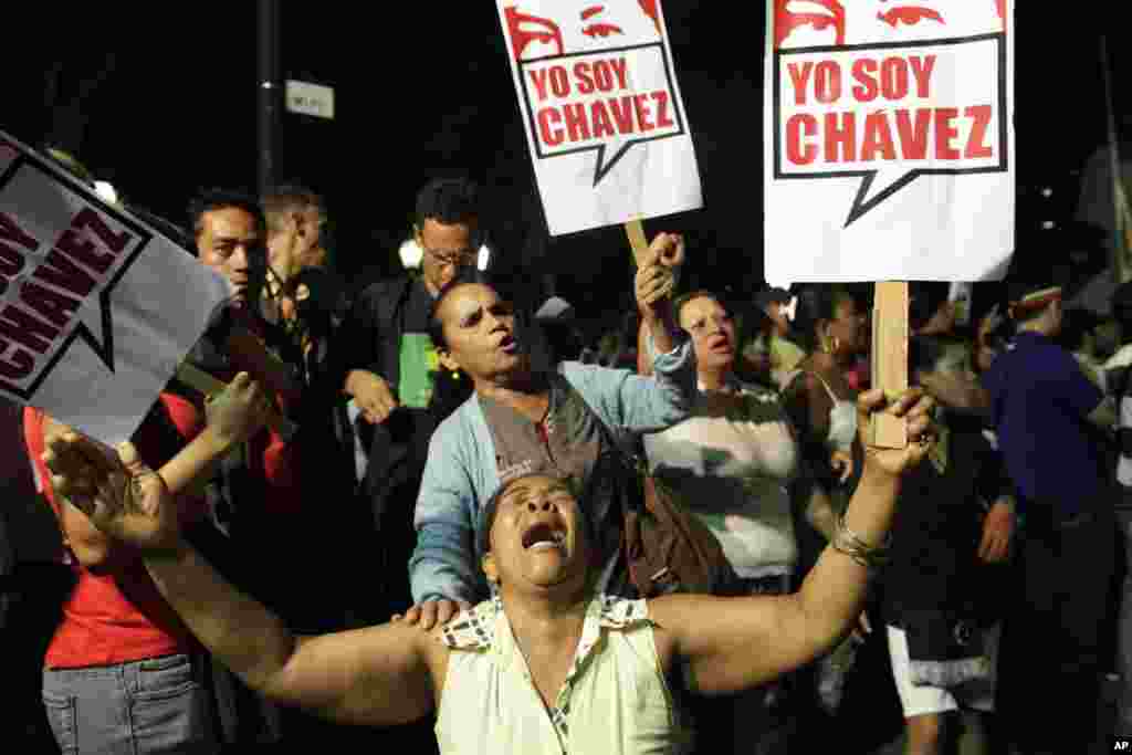 A supporter of Venezuelan President Hugo Chavez cries as she holds a sign that reads in Spanish "I am Chavez," in Bolivar square, Caracas, Venezuela, March 5, 2013.