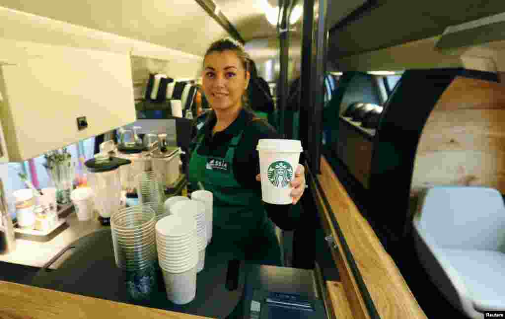 An employee of Starbucks holds a cup of coffee at a new Starbucks store on a train of Swiss rail operator SBB in Zurich. The world's largest coffee chain Starbucks presented its first double-deck store on a SBB Intercity train travelling between the Swiss cities of St. Gallen and Geneva, Nov. 14, 2013.