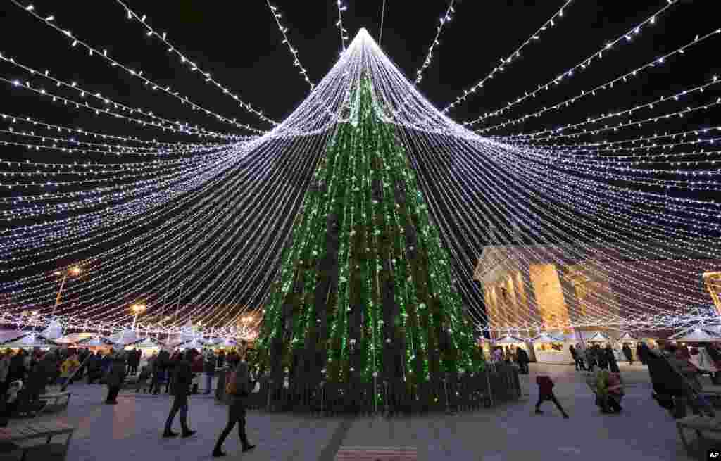 Warga berjalan di sekitar Pohon Natal di Lapangan Katedral di kota Vilnius, Lithuania.